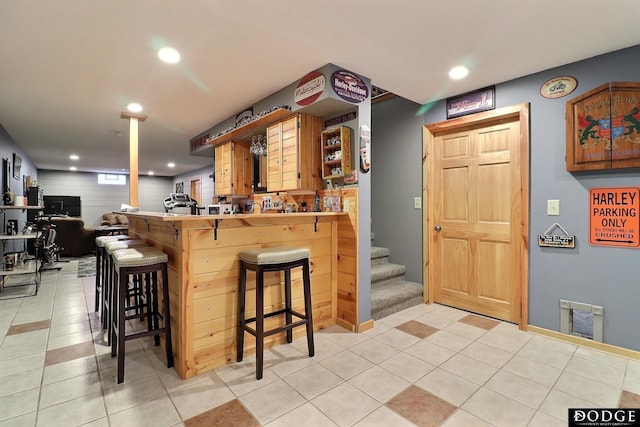 bar with light tile patterned floors, recessed lighting, stairs, and bar