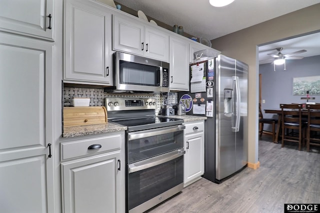 kitchen featuring ceiling fan, decorative backsplash, light wood-style flooring, white cabinets, and stainless steel appliances