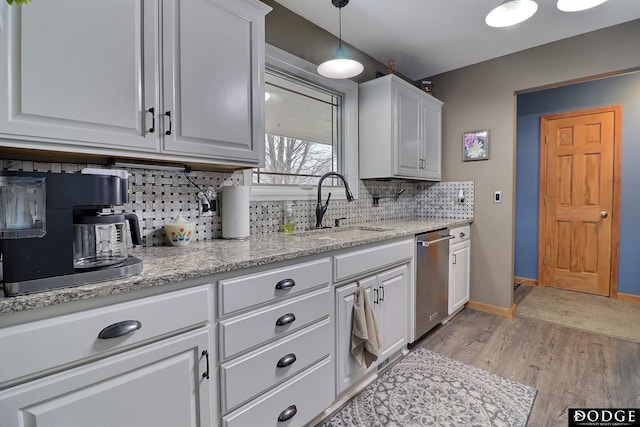 kitchen featuring a sink, backsplash, light wood-style floors, white cabinets, and dishwasher