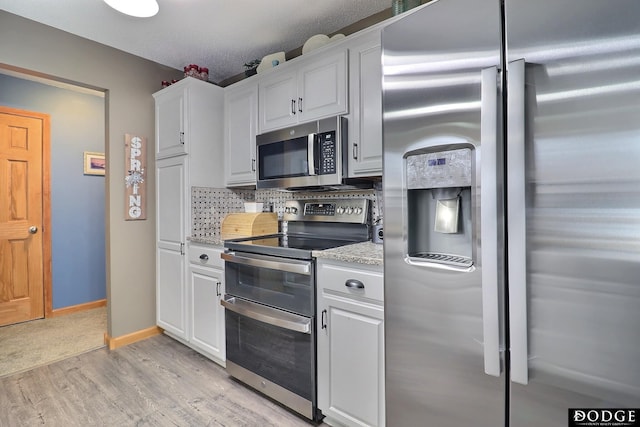 kitchen featuring light wood finished floors, backsplash, white cabinetry, and stainless steel appliances