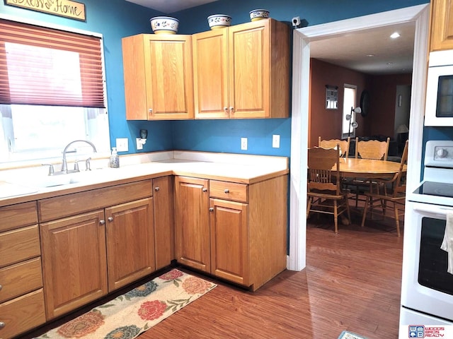 kitchen featuring a sink, range with electric stovetop, wood finished floors, light countertops, and white microwave