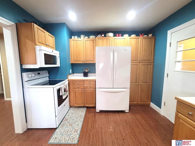 kitchen with white appliances, wood finished floors, light countertops, and baseboards