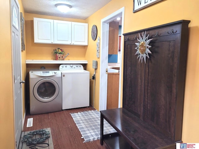 laundry room featuring cabinet space, a textured ceiling, washing machine and dryer, and dark wood-style flooring