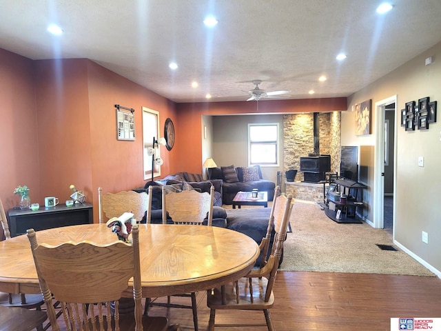 dining room featuring visible vents, a ceiling fan, recessed lighting, baseboards, and a wood stove