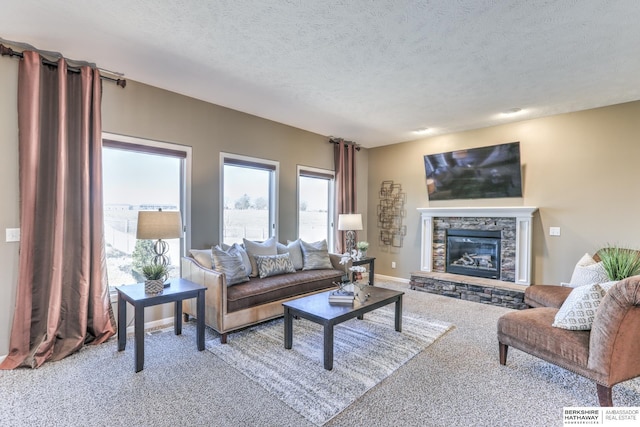 carpeted living room featuring a stone fireplace, baseboards, and a textured ceiling