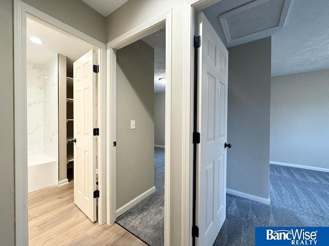 hall featuring wood finished floors, baseboards, and carpet floors