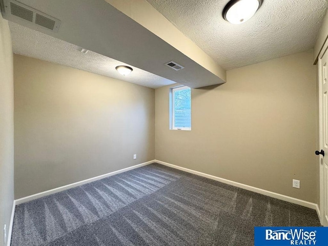 basement featuring baseboards, visible vents, and a textured ceiling