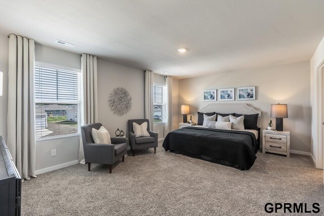 carpeted bedroom featuring visible vents, multiple windows, and baseboards