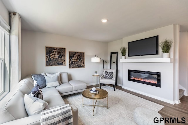 living area featuring recessed lighting, baseboards, wood finished floors, and a glass covered fireplace