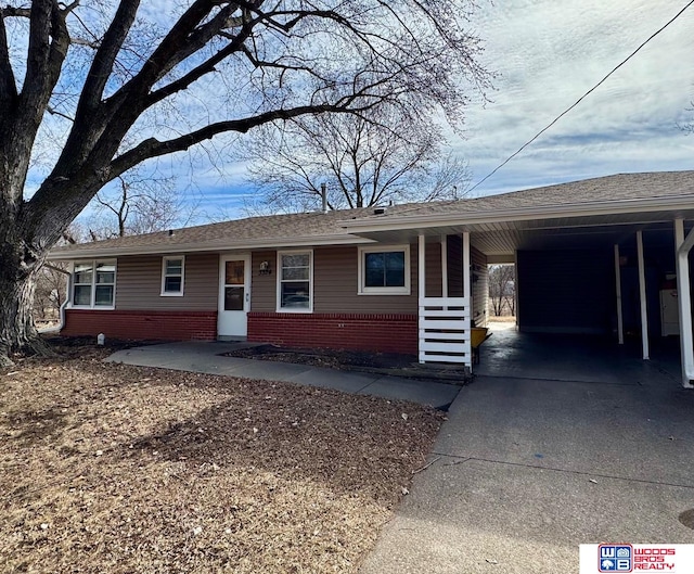 ranch-style home with an attached carport, brick siding, and concrete driveway