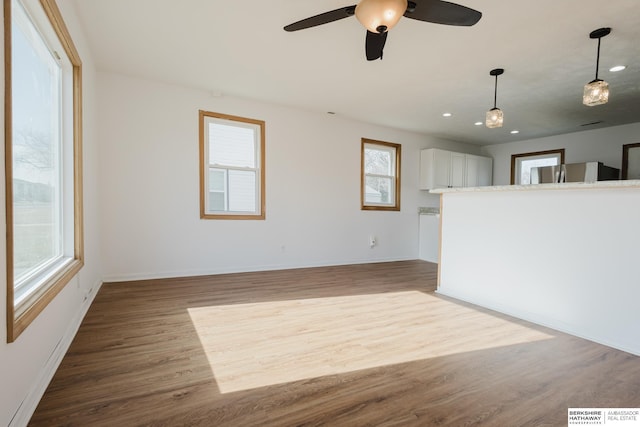 unfurnished living room with plenty of natural light, recessed lighting, baseboards, and wood finished floors