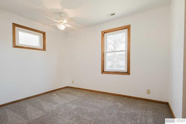 carpeted spare room with visible vents, plenty of natural light, baseboards, and ceiling fan