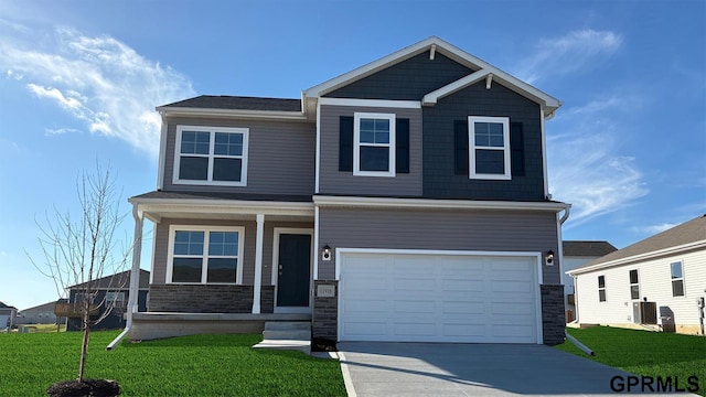 craftsman-style house featuring a front lawn, stone siding, cooling unit, concrete driveway, and an attached garage