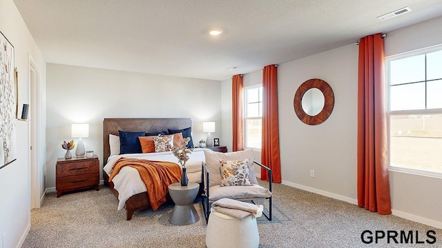 bedroom with visible vents, light carpet, a textured ceiling, and baseboards
