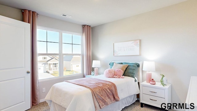 bedroom with light carpet, visible vents, and multiple windows