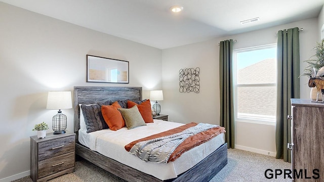 bedroom with baseboards, visible vents, and light carpet