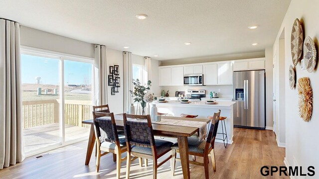 dining area featuring recessed lighting, light wood-type flooring, baseboards, and a textured ceiling