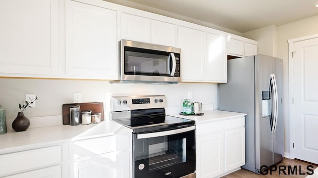 kitchen featuring light wood-style flooring, stainless steel appliances, white cabinets, and light countertops