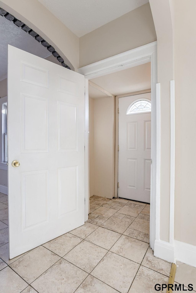 entrance foyer featuring light tile patterned floors, baseboards, and arched walkways