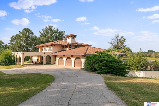 mediterranean / spanish house featuring a tiled roof, a front yard, stucco siding, a garage, and driveway