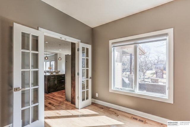 interior space featuring french doors, baseboards, visible vents, and wood finished floors