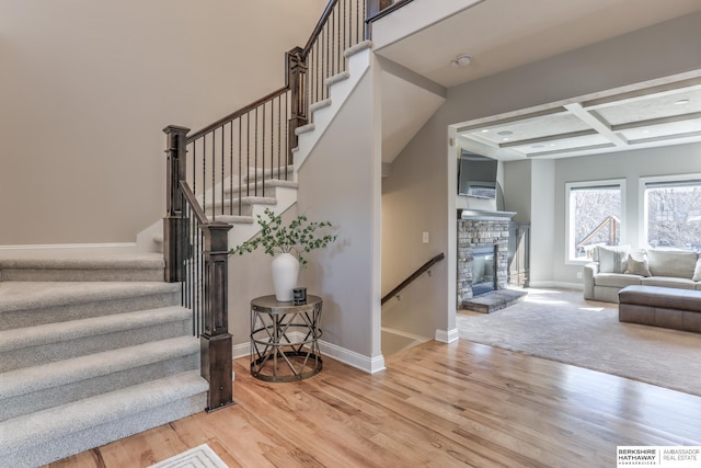 stairway with baseboards, coffered ceiling, and wood finished floors