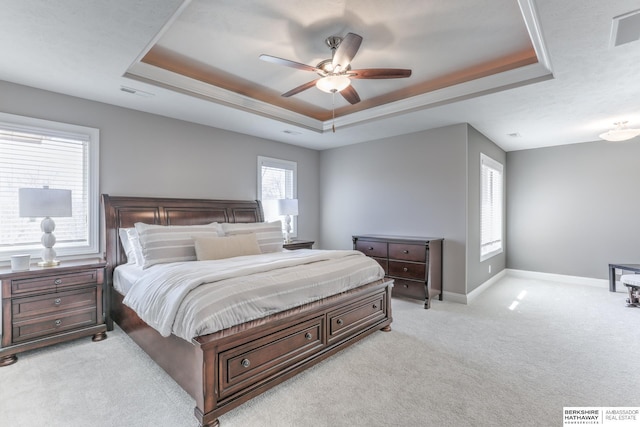 bedroom featuring baseboards, a raised ceiling, light carpet, and visible vents