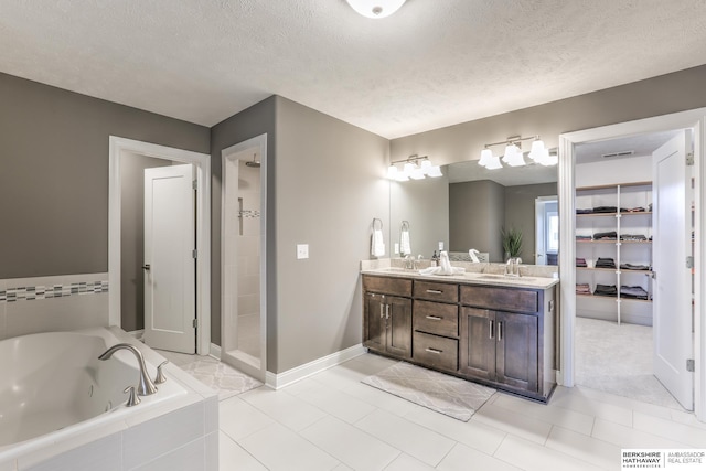 full bathroom featuring a jetted tub, double vanity, a stall shower, a textured ceiling, and a sink