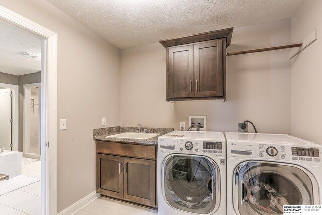 laundry room featuring washer and clothes dryer, light tile patterned floors, cabinet space, a textured ceiling, and a sink