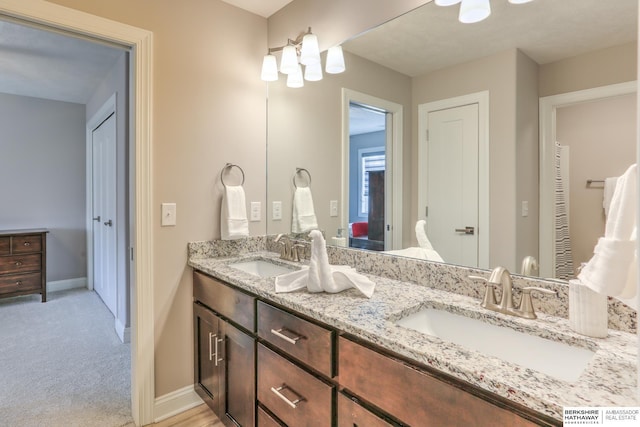 full bath with double vanity, baseboards, and a sink