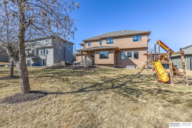 rear view of property with a playground and a yard