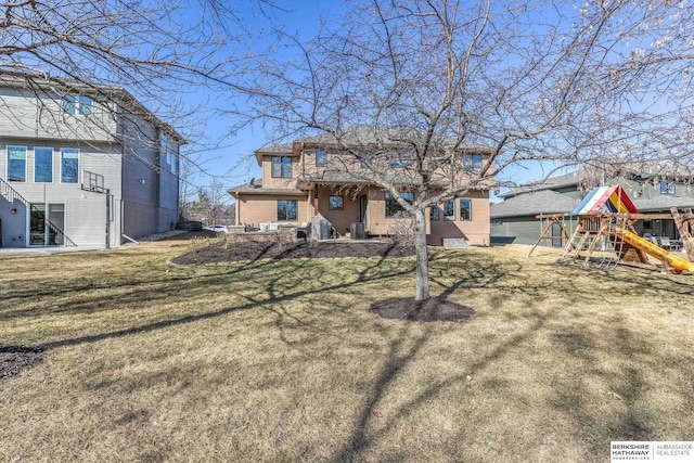 rear view of house featuring a playground and a yard