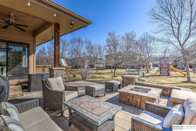 view of patio with an outdoor living space with a fire pit, playground community, and ceiling fan