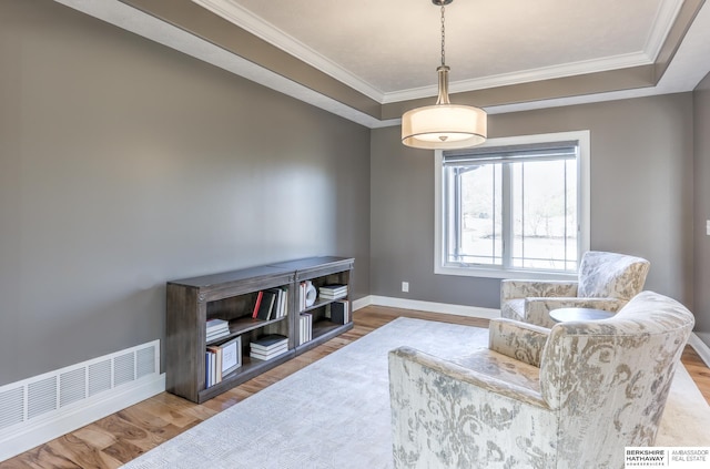 sitting room with ornamental molding, wood finished floors, visible vents, and baseboards