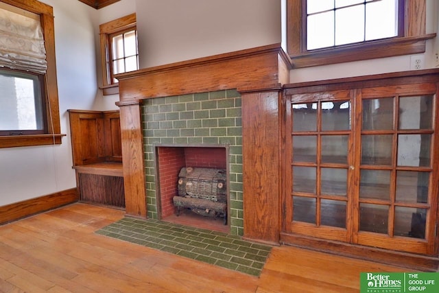 unfurnished living room featuring a fireplace with flush hearth, a high ceiling, baseboards, and wood finished floors