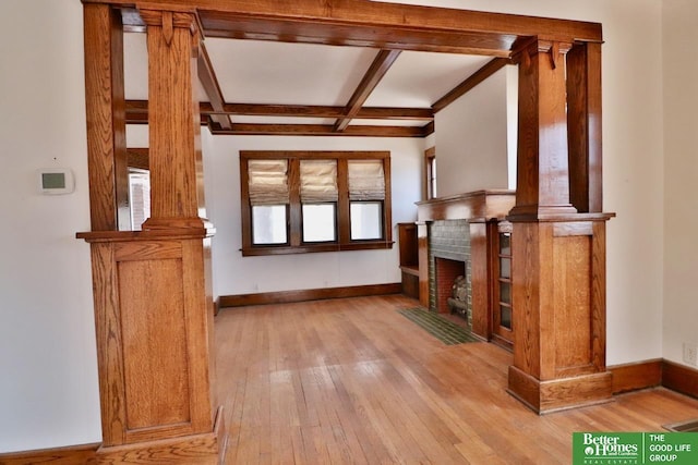 unfurnished living room featuring beam ceiling, wood-type flooring, baseboards, and decorative columns