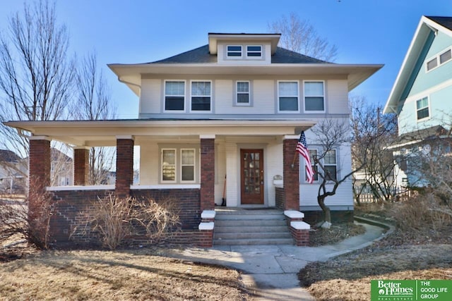 american foursquare style home featuring brick siding and covered porch