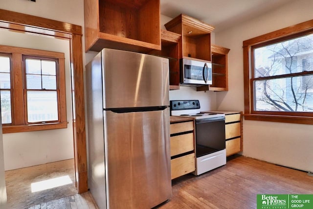 kitchen with a healthy amount of sunlight, appliances with stainless steel finishes, light wood-style floors, and open shelves