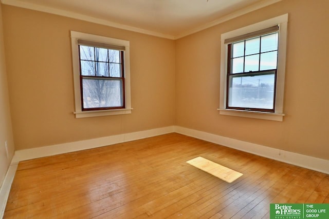 empty room with crown molding, baseboards, and wood-type flooring