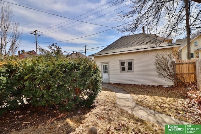 back of property featuring roof with shingles and fence