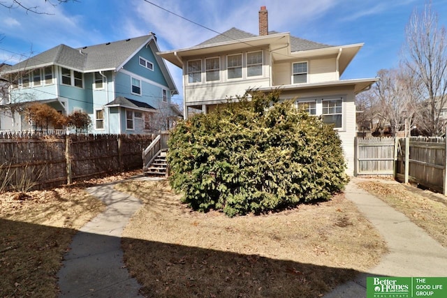 back of property with stairs, fence, and a chimney