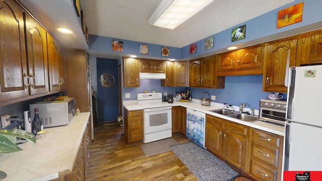 kitchen featuring white appliances, light countertops, under cabinet range hood, and a sink