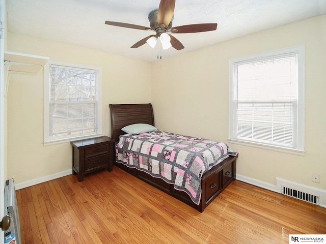 bedroom with visible vents, baseboards, light wood-style floors, and ceiling fan