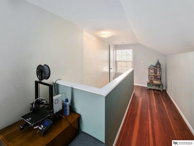 corridor with baseboards, visible vents, dark wood-style flooring, vaulted ceiling, and an upstairs landing