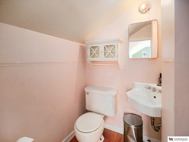 bathroom featuring toilet, lofted ceiling, a sink, wood finished floors, and baseboards