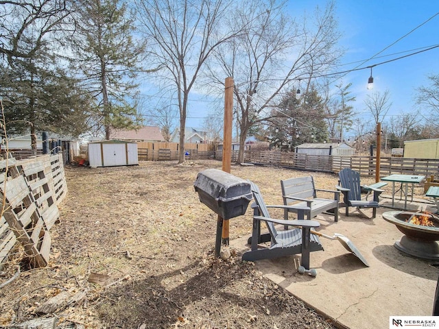 view of yard with an outbuilding, a patio, a fenced backyard, a fire pit, and a storage shed