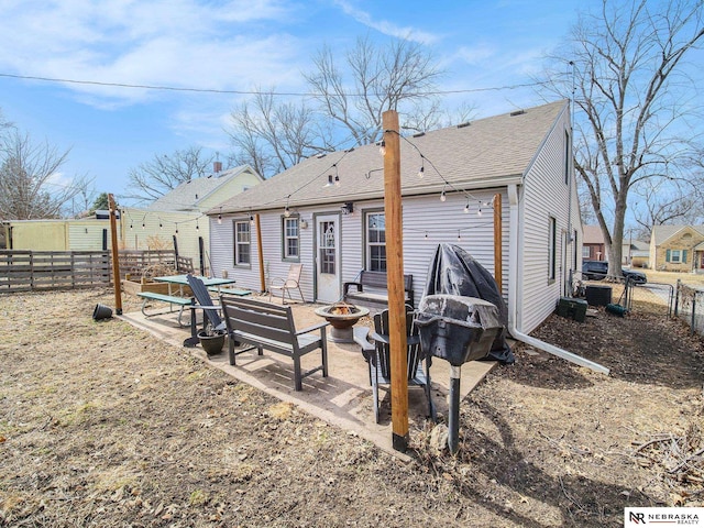 back of house featuring a gate, a fenced backyard, a fire pit, a shingled roof, and a patio area