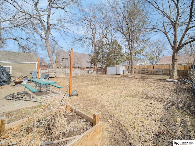 view of yard featuring an outbuilding, a fenced backyard, an outdoor fire pit, and a shed