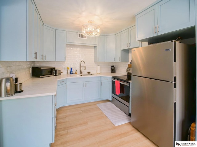 kitchen featuring visible vents, light wood-type flooring, light countertops, stainless steel appliances, and a sink