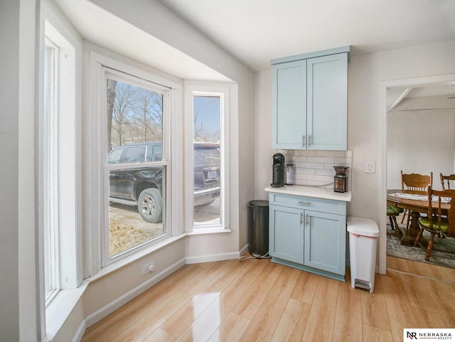 kitchen with light countertops, light wood-style floors, tasteful backsplash, and baseboards